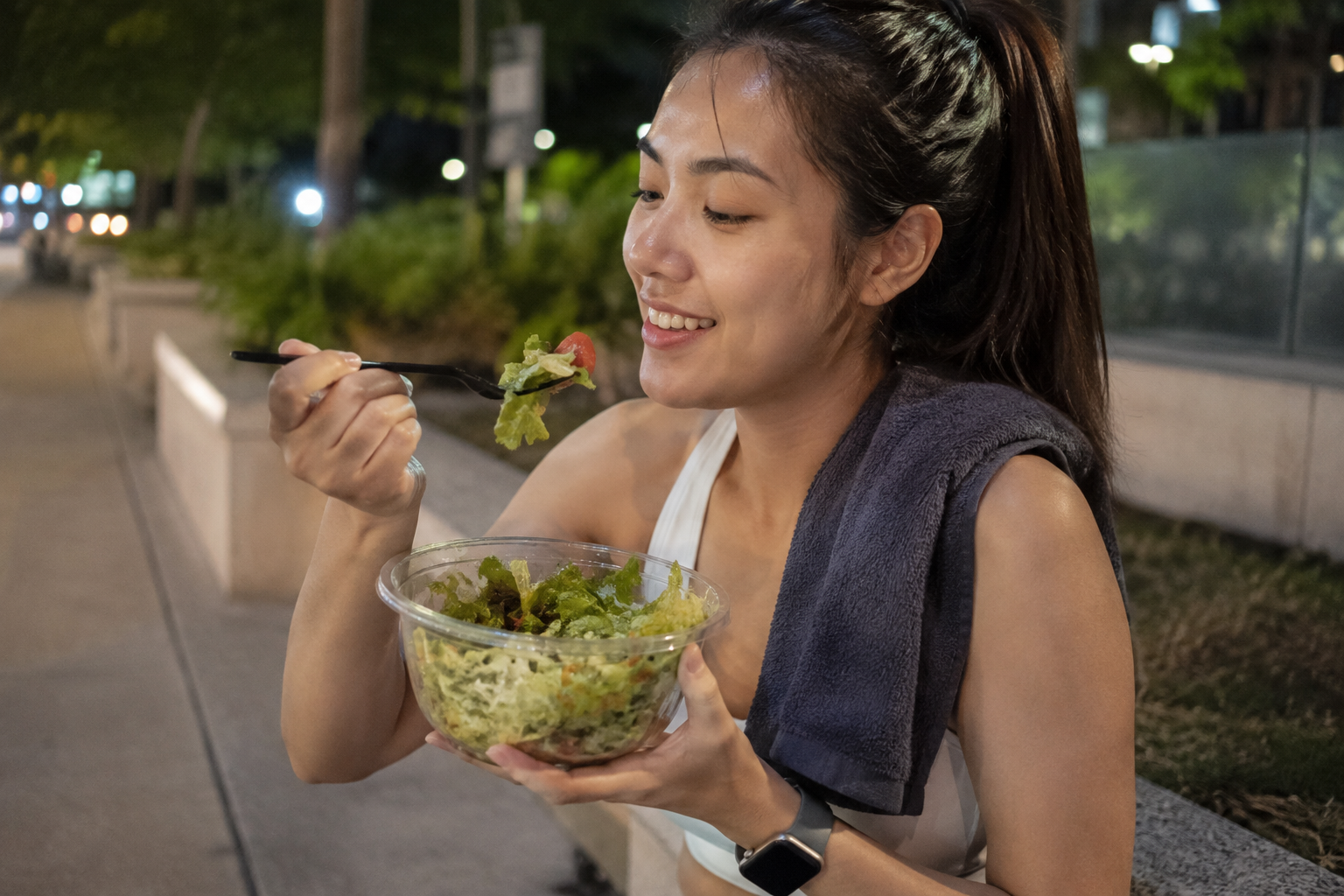 運動結束正在吃著生菜沙拉,健康的女子